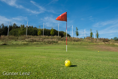 Golfball mit Fahne am Green, Golfplatz